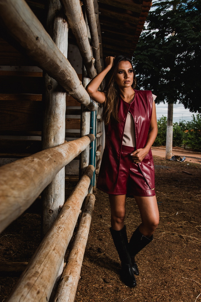 马厩旁穿着栗色皮革无袖夹克的女子