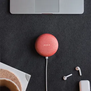 Apple AirPods 旁边黑色表面上的珊瑚 Google Home Mini 平躺摄影