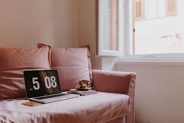 在粉色沙发上放着笔记本电脑的工作场所