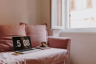 在粉色沙发上放着笔记本电脑的工作场所