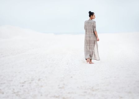 穿着灰色衣服在沙滩上行走的女人