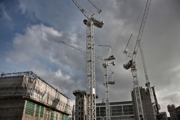 起重机在建筑工地上工作的景象，天空中乌云密布