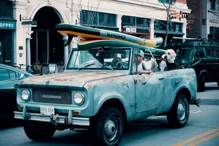 一名男子驾驶皮卡，带着两只大狗和冲浪板