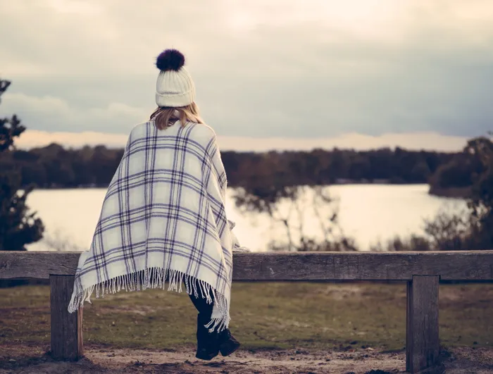 坐在灰色木凳上观看水体的女子