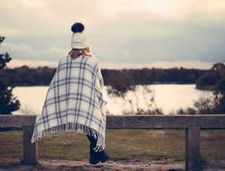 坐在灰色木凳上观看水体的女子