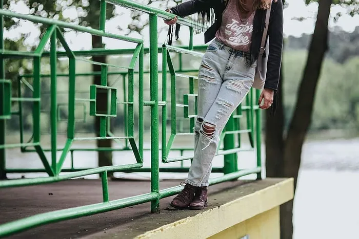 穿着黑色夹克和绿色扶手撕破牛仔裤的金发女人
