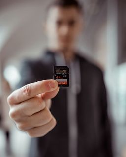 持有Sandisk 64gb Microsd适配器的人