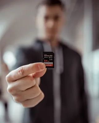 持有Sandisk 64gb Microsd适配器的人