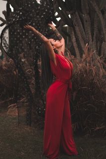 穿着红色套头衫的女人站在植物附近 穿着红色套头衫的女人站在植物附近