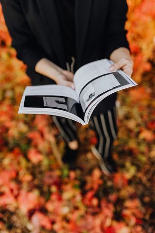 以五颜六色的树叶为背景，拿着格拉夫康夫书的女孩