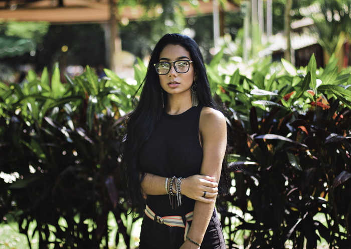 身穿黑色无袖上衣和太阳镜的女子站在那里的照片