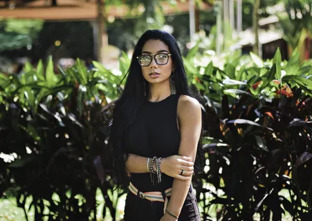 身穿黑色无袖上衣和太阳镜的女子站在那里的照片