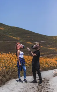 白天，男人和女人在花田附近戴着马面具面对面