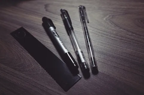 三支圆珠笔和米色木质表面的黑色直尺 三支圆珠笔和米色木质表面的黑色直尺