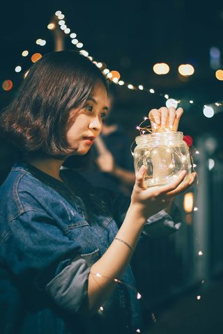 一名女子拿着装有细绳灯的罐子的照片