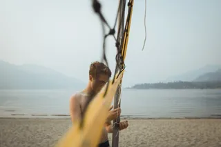 白天站在沙滩上渔网旁的男子