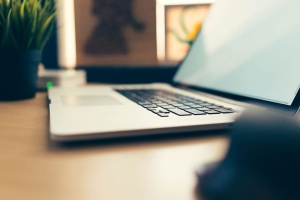 苹果MacBook键盘。打开的白色书本盖放在一张平整的木质桌面上。