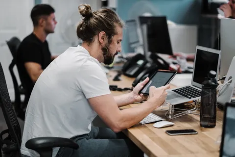 一名男子在关闭的MacBook Air前打开iPad 一名男子在关闭的MacBook Air前打开iPad