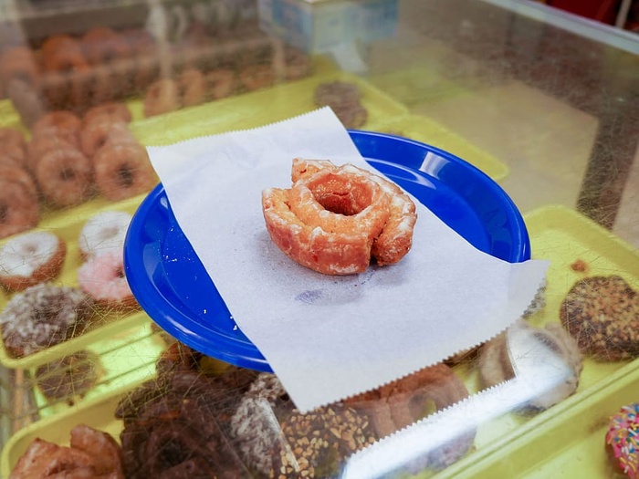 一家甜甜圈店内，一个蓝色盘子上放着一个上釉的蛋糕甜甜圈。