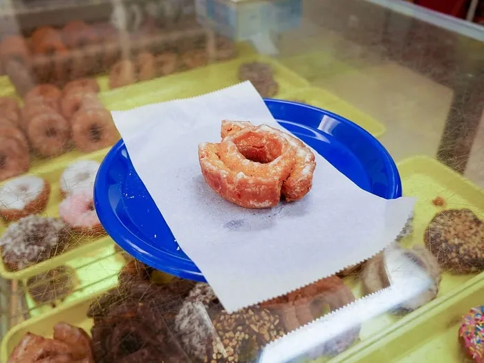 一家甜甜圈店内，一个蓝色盘子上放着一个上釉的蛋糕甜甜圈。