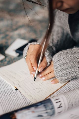 穿着灰色毛衣的女人在组织者里做笔记