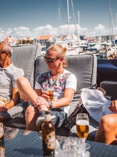 坐在灰色软垫日光躺椅上的男子