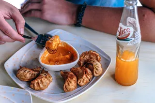 桌子前拿着油炸饺子和苏打水瓶的人