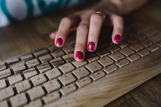 女性手在无线木质键盘上打字的特写