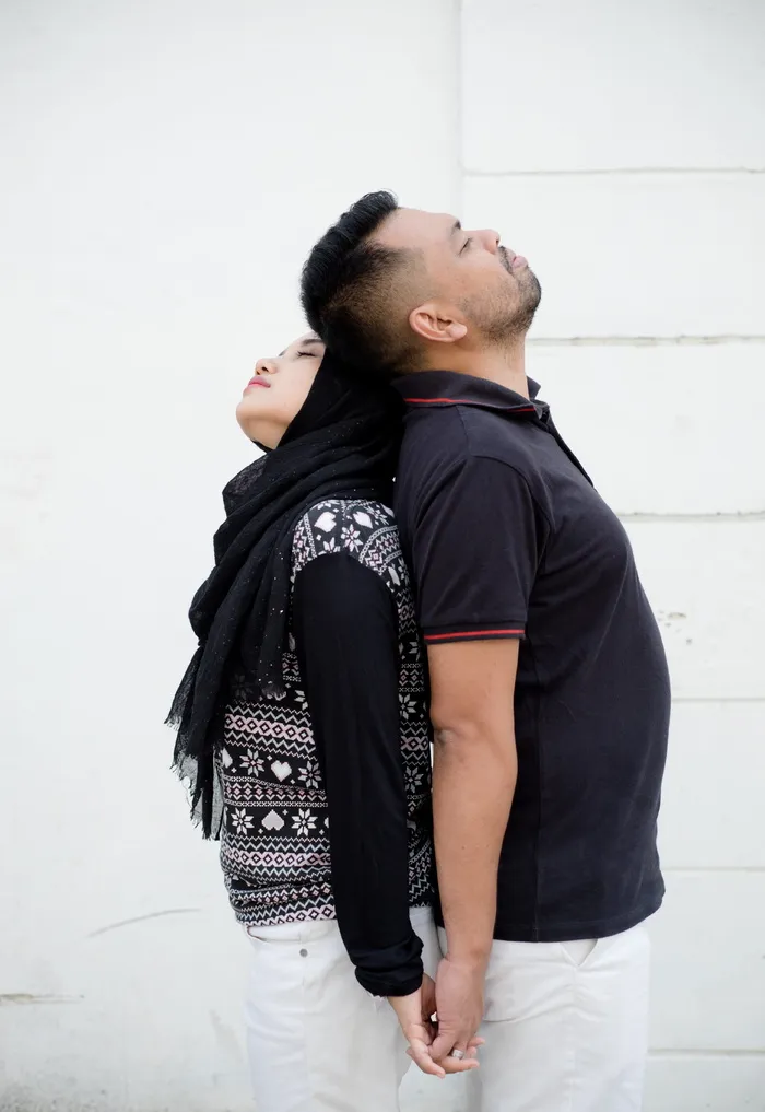 男男女女站在白墙附近，背部平齐