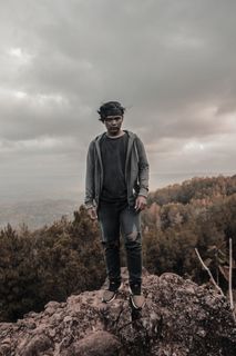 身穿灰色拉链夹克和黑色牛仔裤的男子