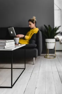 坐在沙发上用笔记本电脑工作的年轻女子