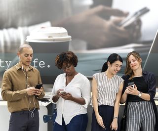 三个女人和一个男人在看智能手机