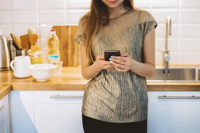 女人在厨房用智能手机发短信