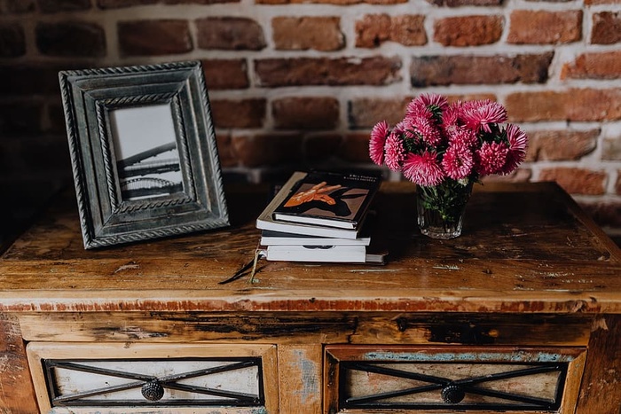 相框、书籍和粉红色的花朵放在木制马桶上的花瓶里