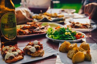 白色盘子上的绿色沙拉，靠近棕色桌子上的烤土豆