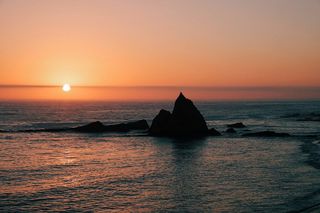 日落时被水体包围的岩层剪影