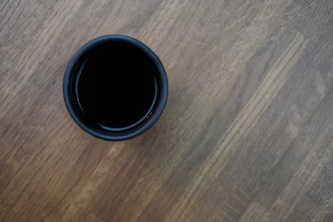 棕色木质表面顶部的黑色塑料杯 棕色木质表面顶部的黑色塑料杯