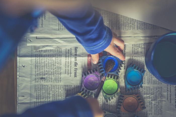 穿着蓝色长袖夹克、手拿紫绿色和蓝色颜料的人