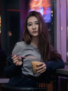 一位女士把他的左肘靠在桌子上，手里拿着装满黄色液体的酒杯