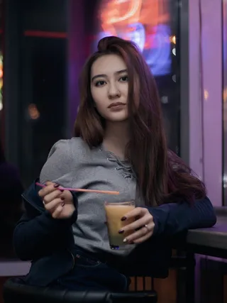 一位女士把他的左肘靠在桌子上，手里拿着装满黄色液体的酒杯