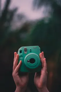 拿着teal Fujifilm Instax即时相机的人的选择性聚焦照片