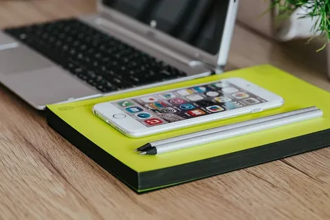 银色宏碁笔记本电脑、一部白色苹果iPhone和一个放在木桌上的记事本 银色宏碁笔记本电脑、一部白色苹果iPhone和一个放在木桌上的记事本