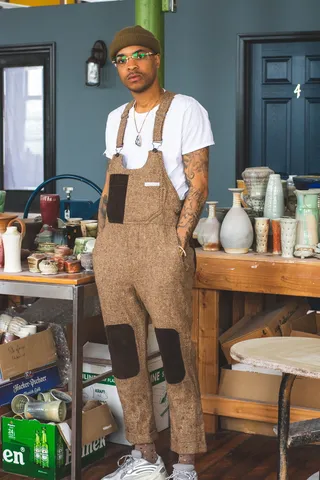 一名身穿粗花呢工作服的男子站在桌子旁，双手插在口袋里