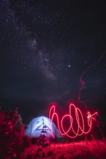 繁星点点的夜空下，照亮的帐篷附近有一道红光