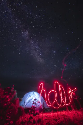 繁星点点的夜空下，照亮的帐篷附近有一道红光