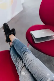 使用笔记本电脑,交叉双腿坐在沙发上的女人 使用笔记本电脑,交叉双腿坐在沙发上的女人