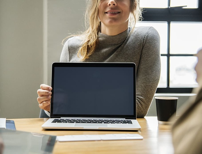 在棕色表面上拿着Macbook Pro的女人