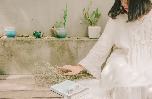 坐在书旁拿着干花的女人