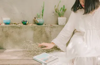 坐在书旁拿着干花的女人