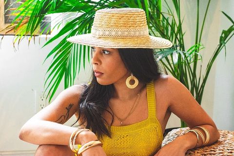 一位戴太阳帽、穿着黄色上衣的女士坐在椅子上向外看的照片